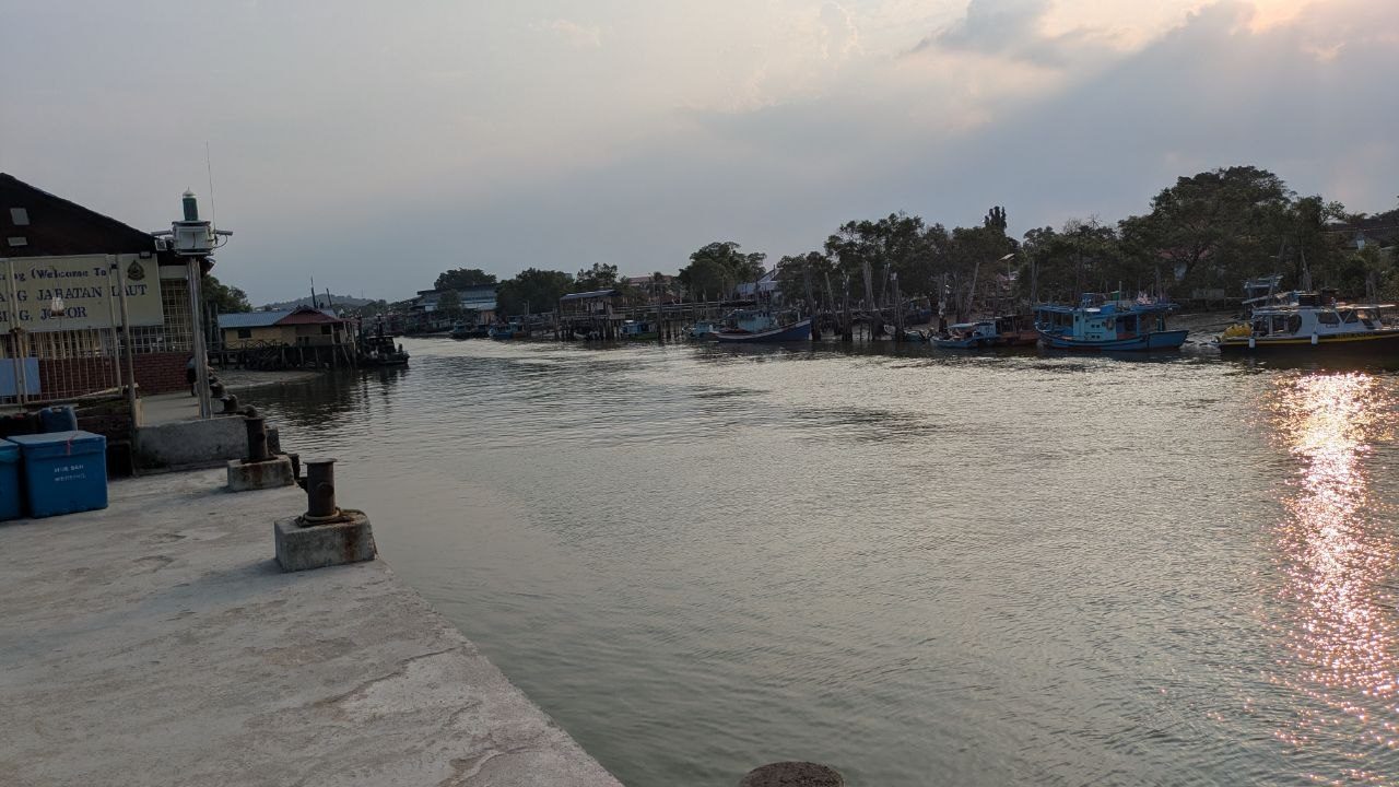 View from the quay across the mouth of the Mersing river, the marine department building on the left, fishing boats along the far bank.