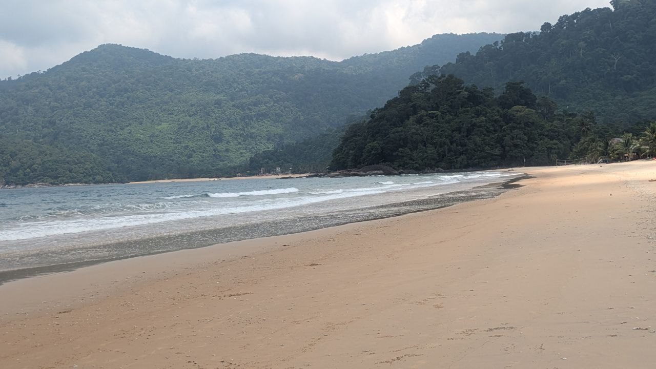 Looking along the bay at Juara: surf in several rows, two wooded ridges behind it reaching down to the water.